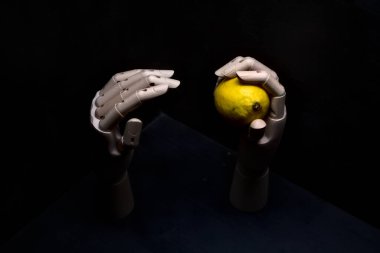 Biri limonu ararken diğeri limonu tutan tahta bir el.