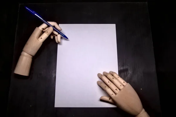 两只木制的手在白纸上书写 — 图库照片