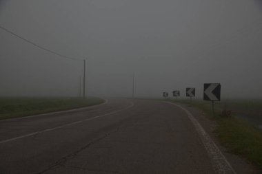 Sonbaharın sonlarında sisli bir günde İtalya kırsalında tarla ile çevrili bir yol.