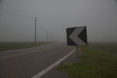 Sonbaharın sonlarında sisli bir günde İtalya kırsalında tarla ile çevrili bir yol.