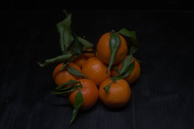 Siyah bir yüzey üzerinde mandalinalar