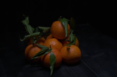 Siyah bir yüzey üzerinde mandalinalar