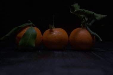 Siyah bir yüzey üzerinde mandalinalar