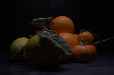 Siyah bir yüzey üzerinde portakal ve limon.