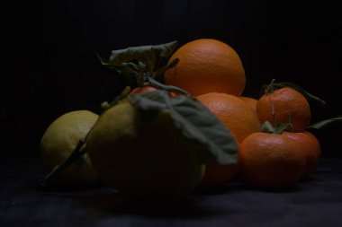 Siyah bir yüzey üzerinde portakal ve limon.