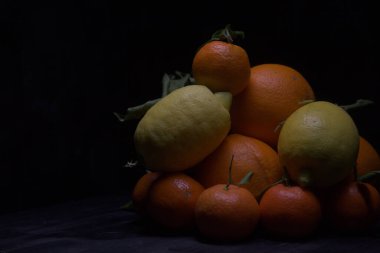 Siyah bir yüzey üzerinde portakal ve limon.