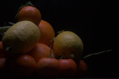 Siyah bir yüzey üzerinde portakal ve limon.