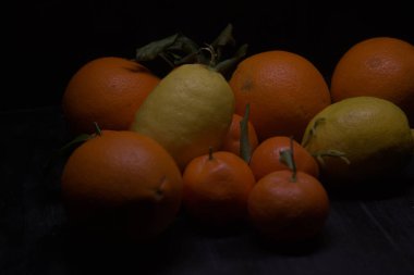 Siyah bir yüzey üzerinde portakal ve limon.