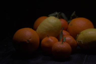 Siyah bir yüzey üzerinde portakal ve limon.