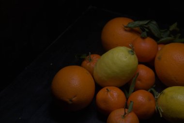 Siyah bir yüzey üzerinde portakal ve limon.