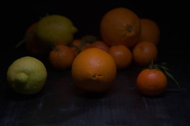 Siyah bir yüzey üzerinde portakal ve limon.