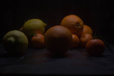 Siyah bir yüzey üzerinde portakal ve limon.