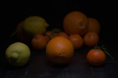 Siyah bir yüzey üzerinde portakal ve limon.