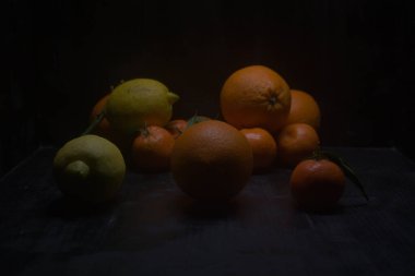 Siyah bir yüzey üzerinde portakal ve limon.