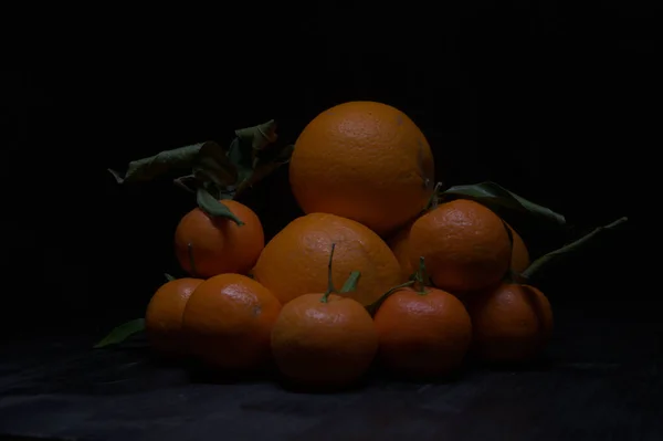 Πορτοκάλια Και Μανταρίνια Στοιβαγμένα Μαύρη Επιφάνεια — Φωτογραφία Αρχείου
