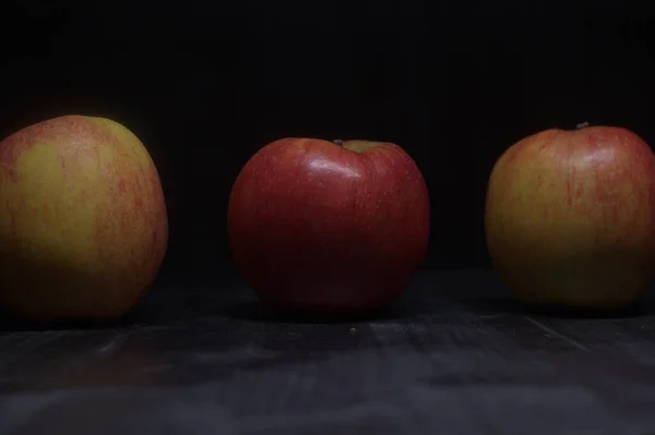 Red and yellow apples on a black surface