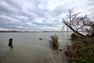 Kışın İtalya kırsalında bulutlu bir günde bir nehrin kıyısında