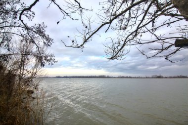 Kışın İtalya kırsalında bulutlu bir günde bir nehrin kıyısında