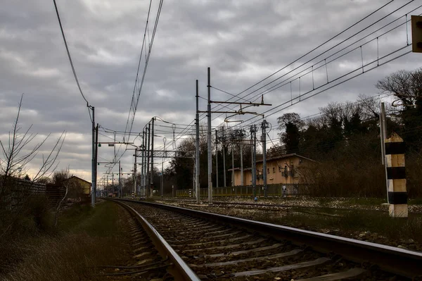 Railroad tracks next to a station in the outskirts of an italian town in winter