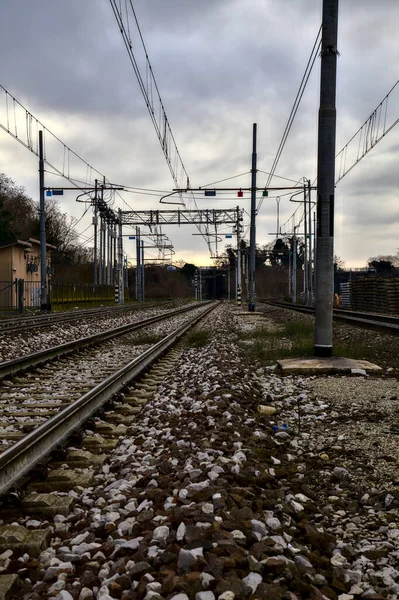Railroad tracks next to a station in the outskirts of an italian town in winter