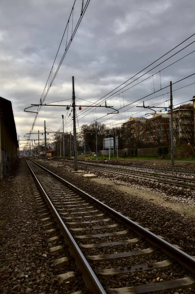 Railroad tracks next to a station in the outskirts of an italian town in winter