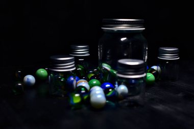 Siyah bir yüzey üzerinde renkli misketlerle dolu kavanoz.