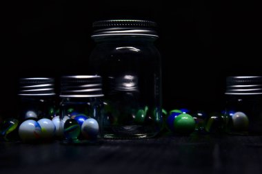 Siyah bir yüzey üzerinde renkli misketlerle dolu kavanoz.