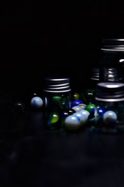 Siyah bir yüzey üzerinde renkli misketlerle dolu kavanoz.