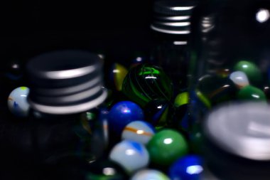 Siyah bir yüzey üzerinde renkli misketlerle dolu kavanoz.