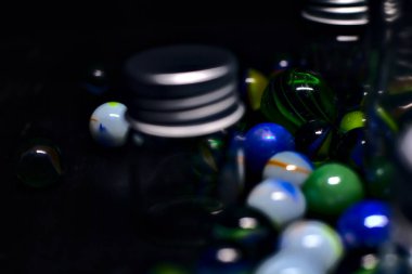 Siyah bir yüzey üzerinde renkli misketlerle dolu kavanoz.