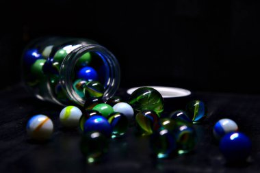 Siyah bir yüzey üzerinde renkli misketlerle dolu kavanoz.