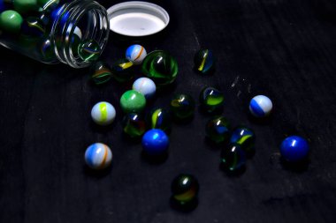 Siyah bir yüzey üzerinde renkli misketlerle dolu kavanoz.