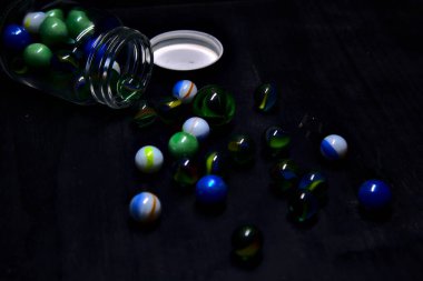 Siyah bir yüzey üzerinde renkli misketlerle dolu kavanoz.