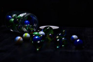 Siyah bir yüzey üzerinde renkli misketlerle dolu kavanoz.