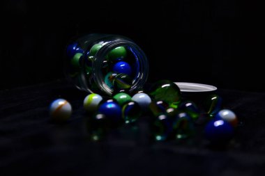 Siyah bir yüzey üzerinde renkli misketlerle dolu kavanoz.