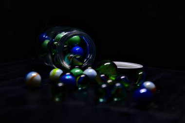 Siyah bir yüzey üzerinde renkli misketlerle dolu kavanoz.