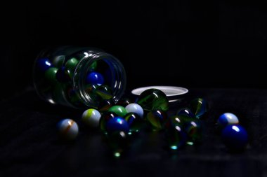 Siyah bir yüzey üzerinde renkli misketlerle dolu kavanoz.