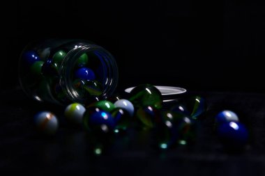 Siyah bir yüzey üzerinde renkli misketlerle dolu kavanoz.