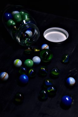 Siyah bir yüzey üzerinde renkli misketlerle dolu kavanoz.