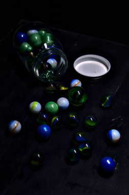 Siyah bir yüzey üzerinde renkli misketlerle dolu kavanoz.