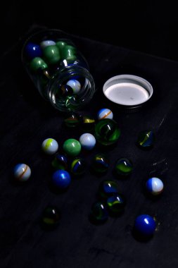 Siyah bir yüzey üzerinde renkli misketlerle dolu kavanoz.