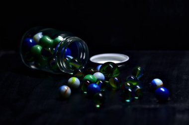 Siyah bir yüzey üzerinde renkli misketlerle dolu kavanoz.