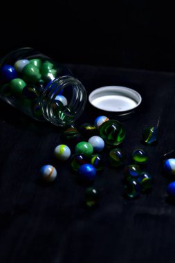 Siyah bir yüzey üzerinde renkli misketlerle dolu kavanoz.