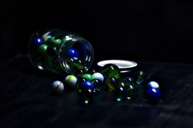 Siyah bir yüzey üzerinde renkli misketlerle dolu kavanoz.