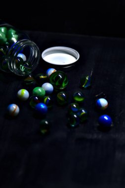 Siyah bir yüzey üzerinde renkli misketlerle dolu kavanoz.