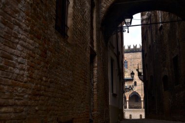 Uzakta bir kale cephesi olan bir İtalyan kasabasında sokak.