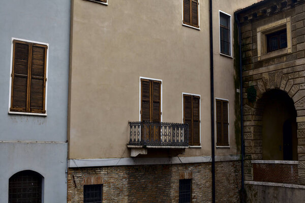 Balcony in a facade with all of the other windows in it with shutters closed