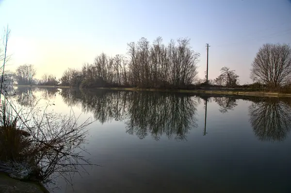 Řeka Lemovaná Holými Stromy Odlesky Vrhanými Vodě Italském Venkově — Stock fotografie