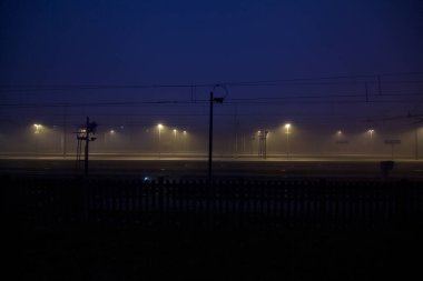 Gün batımında, sisli bir günde, uzaktan görülen tren istasyonu.