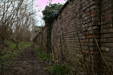 Tuğla bir sınır duvarı ve italyan kırsalında bir set ile çevrili çamurlu bir yol.